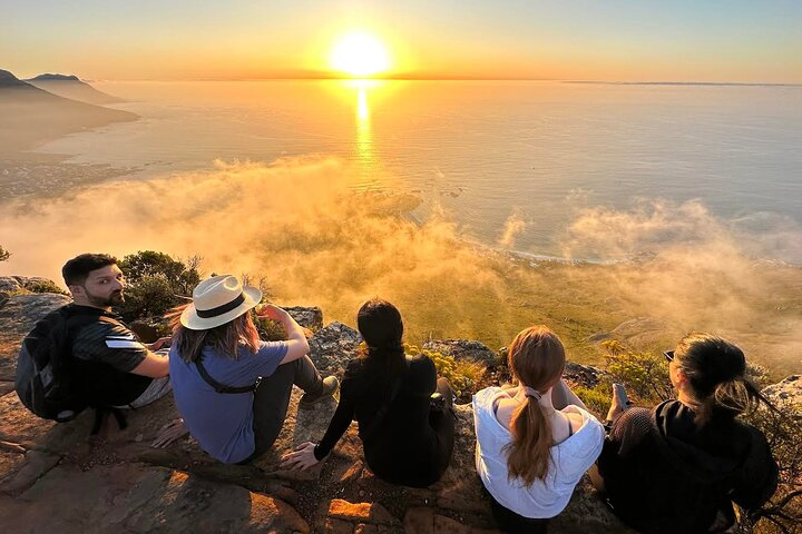 Experience the stunning view of the sun rising over the Atlantic Ocean surrounded by friends atop Lion's Head where breathtaking scenery meets unforgettable moments.